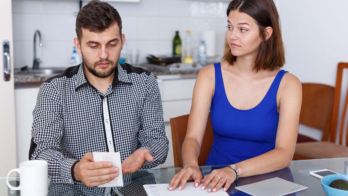 Mann und Frau sitzen in der Küche und sorgen sich wegen Rechnungen. 