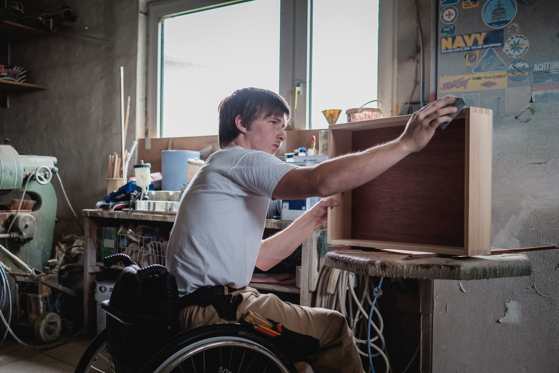 Junger Mann im Rollstuhl arbeitet 
