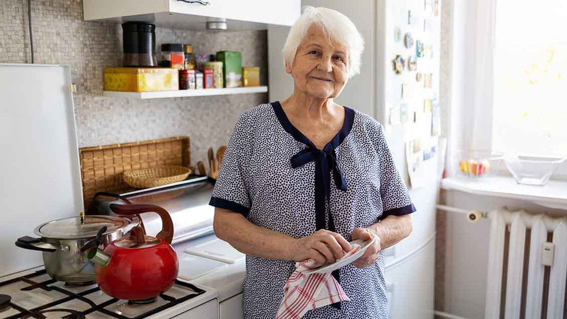 Alte Frau steht in ihrer Küche