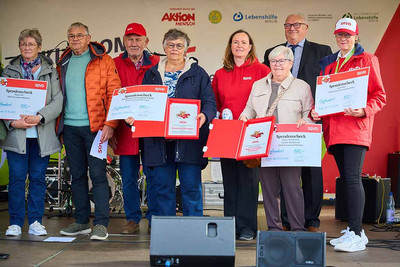 Acht Personen, teilweise mit Urkunden auf einer Bühne.