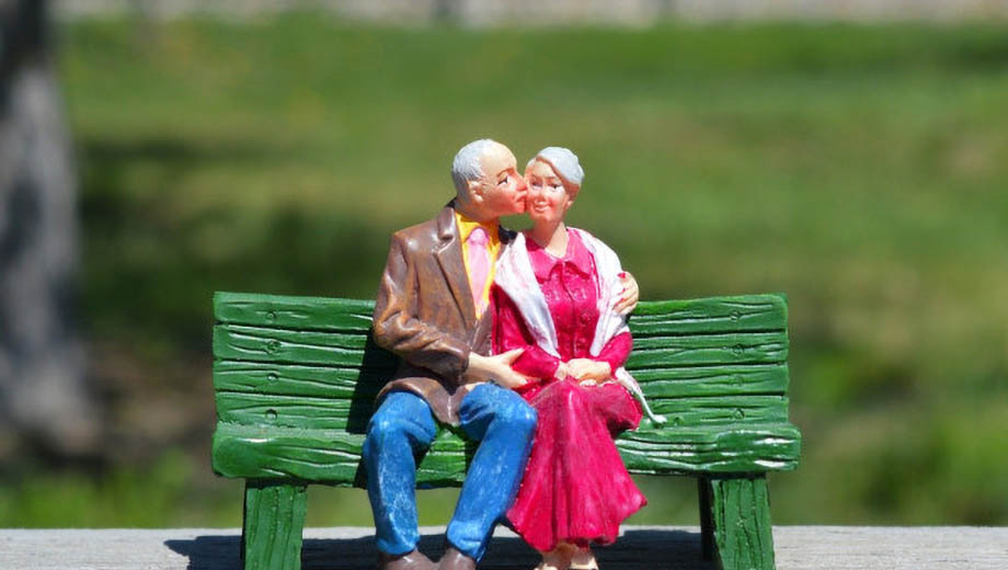 Miniatur eines alten Ehepaars auf einer grünen Bank