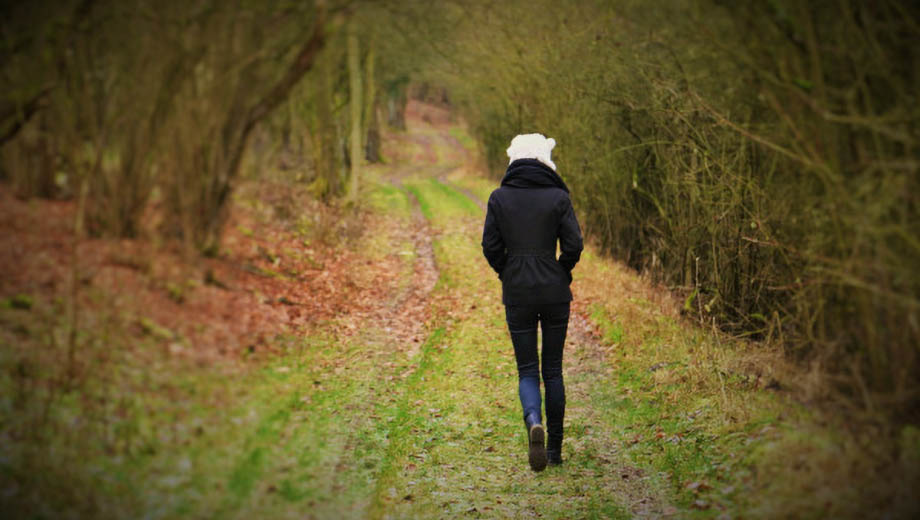 Frau läuft allein durch einen Wald.