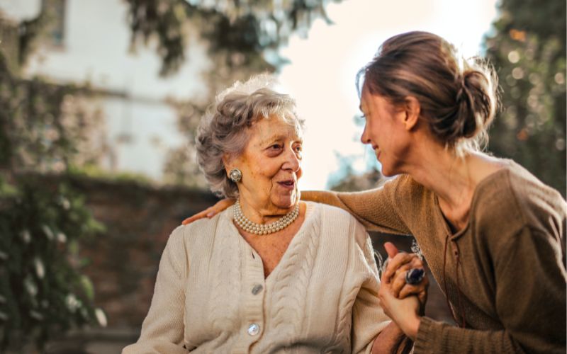 Lohnersatzleistung für pflegende Angehörige Auf dem Bild ist eine ältere Dame zu sehen. Eine jüngere Frau, vielleicht ihre Tochter, legt den Arm um sie.