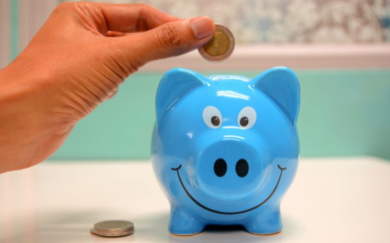Pflegeversicherung zur Vollversicherung für alle ausbauen! Ein blaues Sparschwein wird mit einer Euro-Münze gefüttert.
